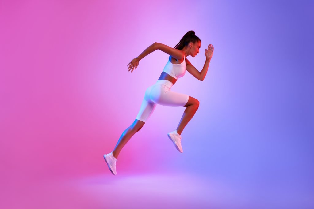 Woman running with colourful background Fit Trainers